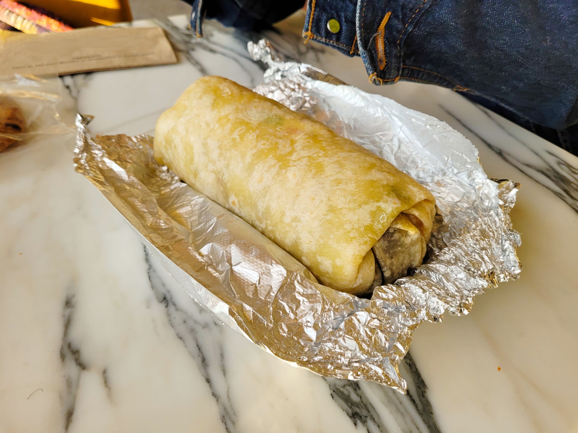 Freshly Made Burrito Wrapped in Foil on Marble Table