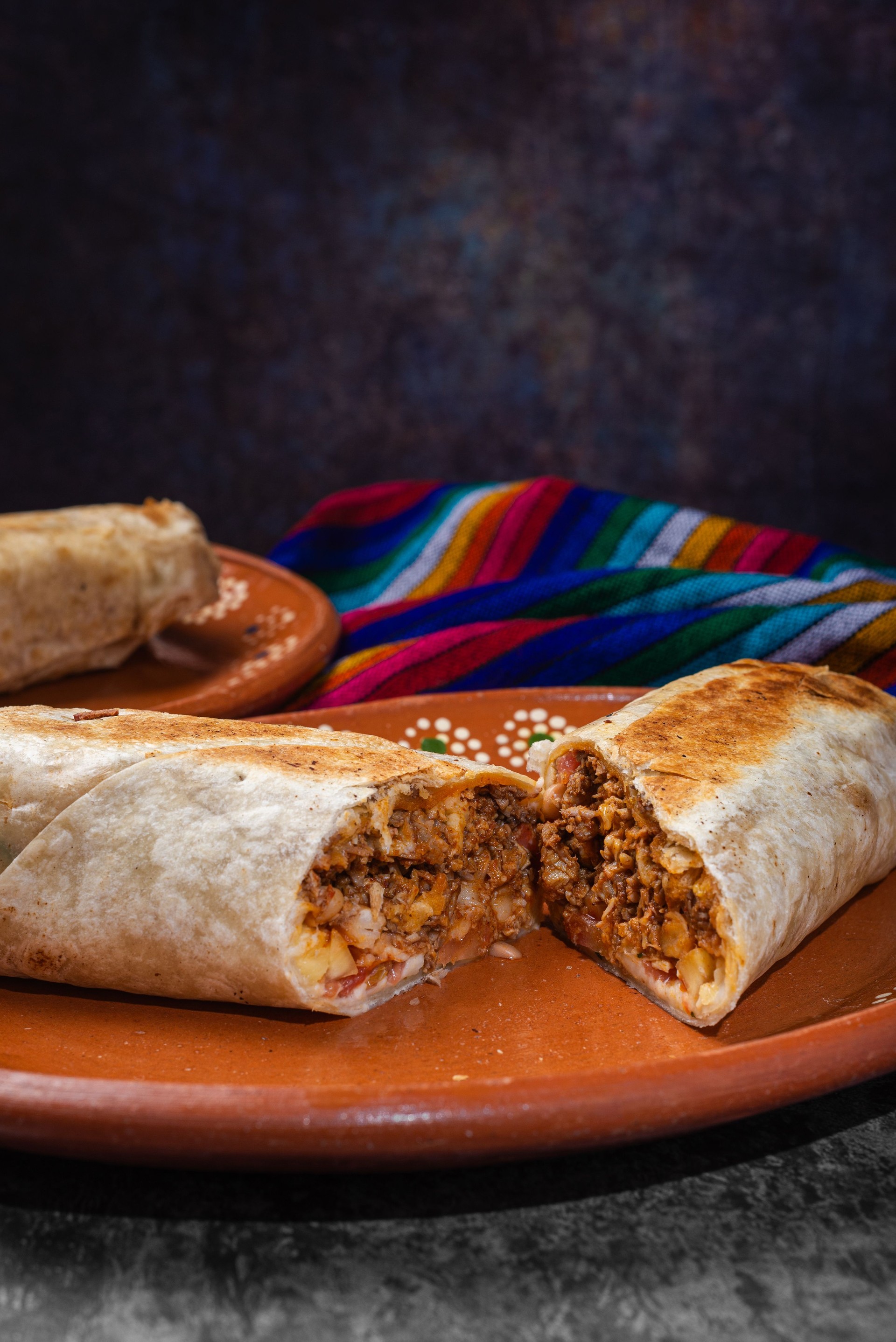 Mexican burrito cut on a clay plate. Mexican fast food.